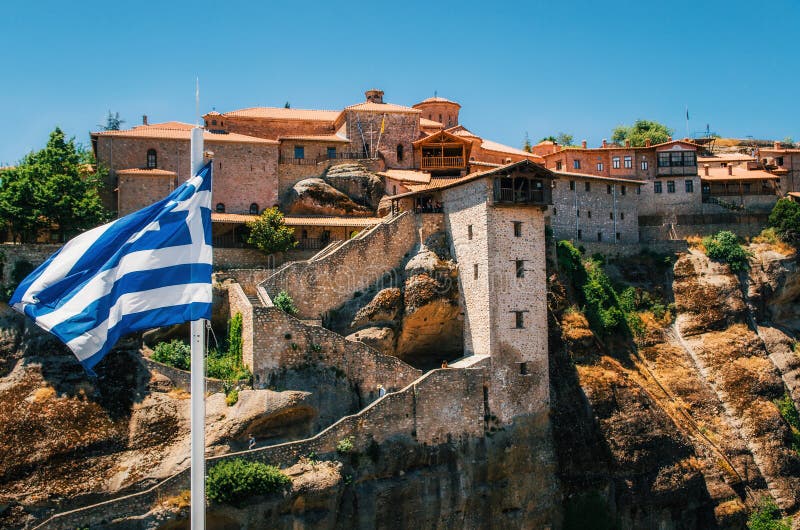 Греческий флаг перед святым монастырем большого Meteoron в Meteora, Греции стоковое фото rf Греческий флаг перед святым монастырем большого Meteoron в Meteora, Греции стоковое фото rf