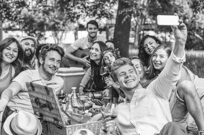 Группа в составе друзья делая барбекю пикника и принимая selfie с мобильным смартфоном в парке на открытом воздухе стоковое фото rf Группа в составе друзья делая барбекю пикника и принимая selfie с мобильным смартфоном в парке на открытом воздухе стоковое фото rf