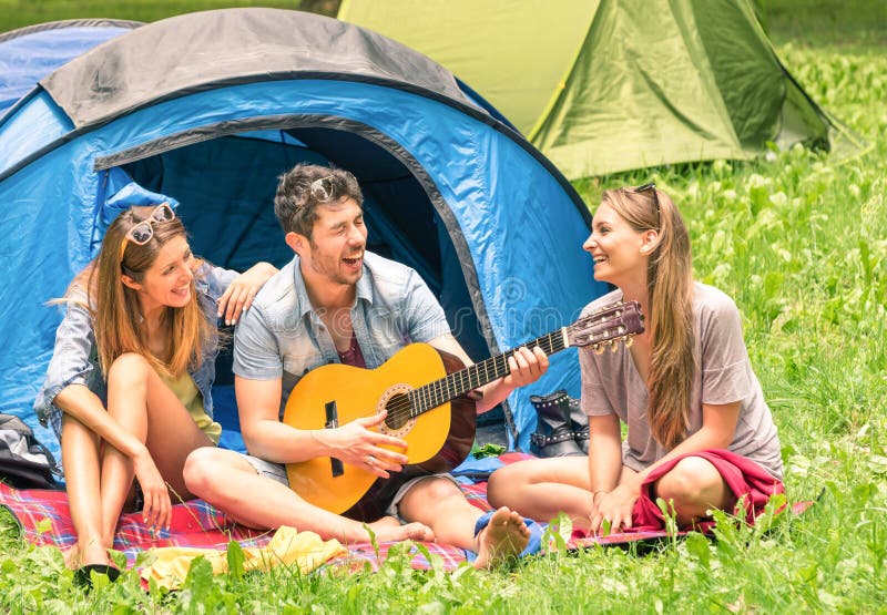 Группа в составе лучшие други поя и имея потеху располагаясь лагерем outdoors стоковое фото rf