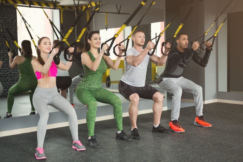 Группа выполняя тренировку подвеса TRX в спортзале стоковые фото Группа выполняя тренировку подвеса TRX в спортзале стоковые фото