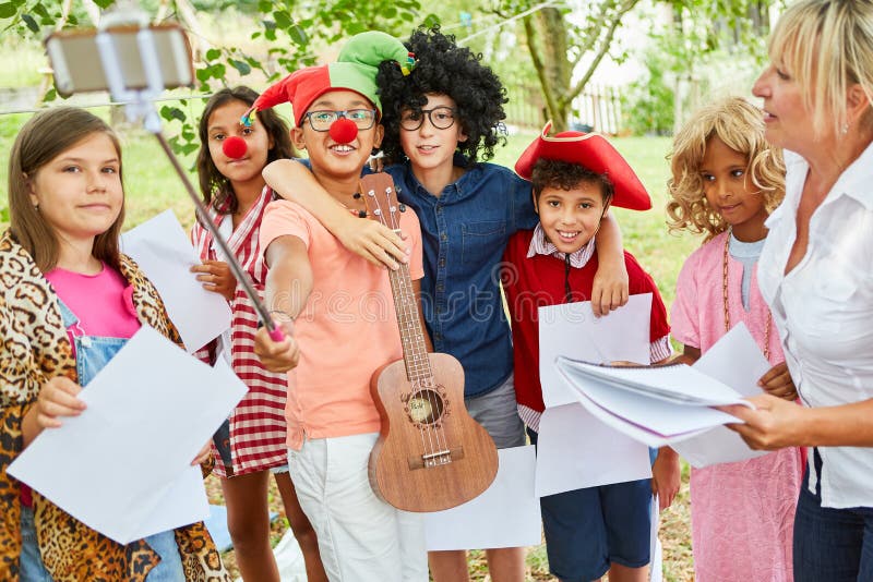 Children theater group or in disguise at the carnival makes selfie with selfie stick. Children theater group or in disguise at the carnival makes selfie with selfie stick