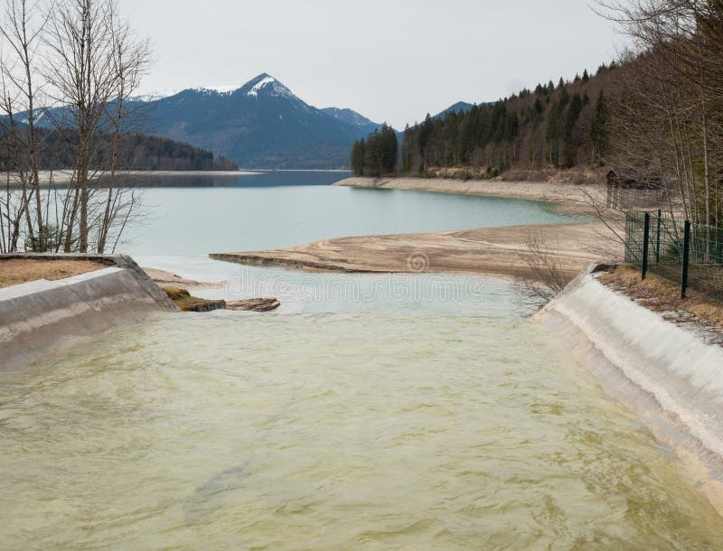 Грязная вода после ночного шторма стекает из гор в голубое озеро Вальчензее Доломиты Альпы стоковые фото