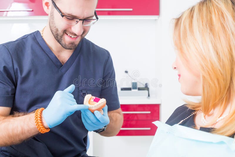 Дантист explaing зубоврачебная обработка с denture к женскому пациенту стоковые фото Дантист explaing зубоврачебная обработка с denture к женскому пациенту стоковые фото