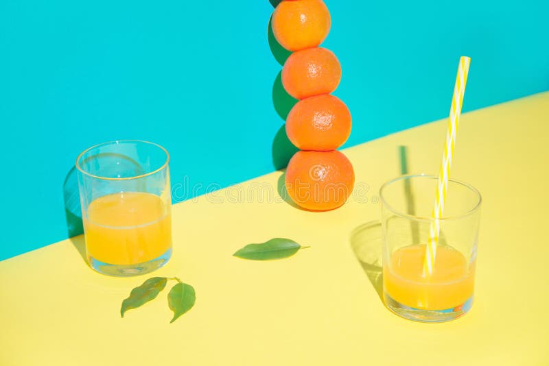 Two cocktail glasses with drinking straws. A vertical pyramid of tangerines. Blue background. Two cocktail glasses with drinking straws. A vertical pyramid of tangerines. Blue background