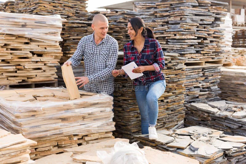 Couple of clients checkin quality of natural stone tiles at warehouse of building materials. Couple of clients checkin quality of natural stone tiles at warehouse of building materials