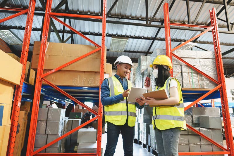 Two warehouse workers in white uniforms and yellow helmets on heads standing and talking about job. Two warehouse workers in white uniforms and yellow helmets on heads standing and talking about job.