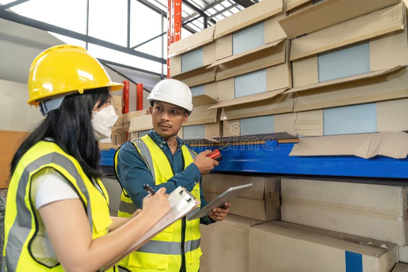 Two smile warehouse workers in uniforms and yellow helmets on heads standing and talking about job. adviser. Two smile warehouse workers in uniforms and yellow helmets on heads standing and talking about job. adviser.