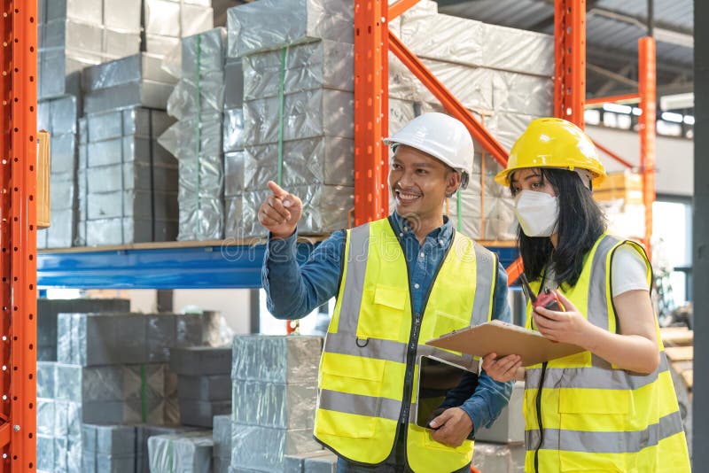 Two smile warehouse workers in white uniforms and yellow helmets on heads standing and talking about job. Two smile warehouse workers in white uniforms and yellow helmets on heads standing and talking about job.