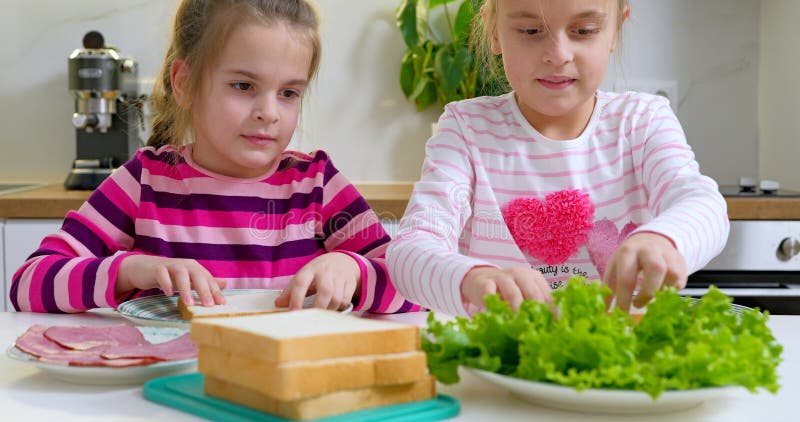 две девочки делают бутерброды на кухне. стоковое изображение rf