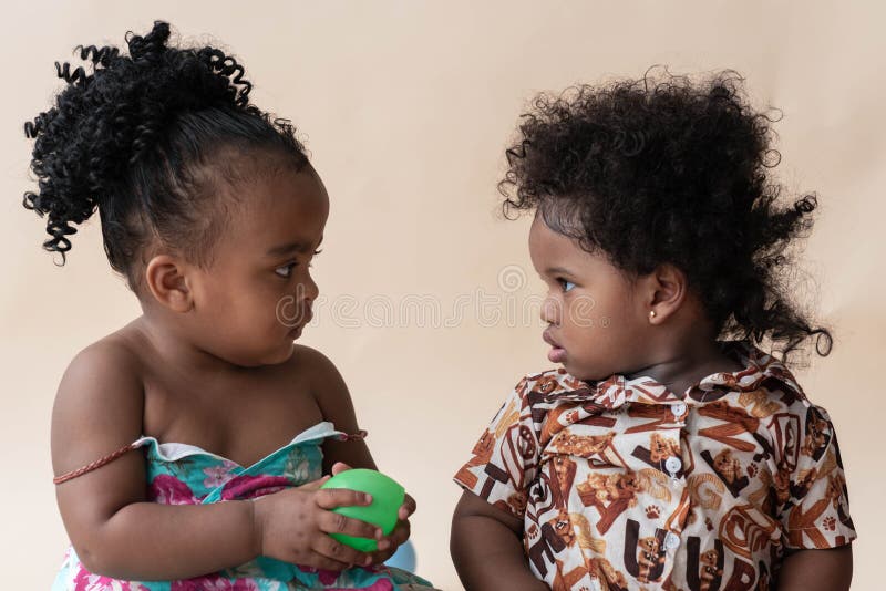 Two Nigerian girls, ages 2 and 1, with beautiful curly hairstyles on a colored background. African family concept. Two Nigerian girls, ages 2 and 1, with beautiful curly hairstyles on a colored background. African family concept