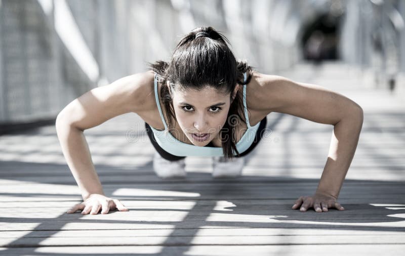 Young beautiful and athletic sport woman doing push up before running in urban training workout on modern metal city bridge in female runner body care concept. Young beautiful and athletic sport woman doing push up before running in urban training workout on modern metal city bridge in female runner body care concept