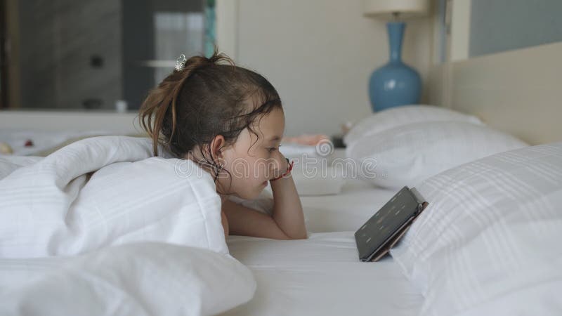 Girl lay in bed under the blanket and watched cartoons on tablet PC stock video - Video counting cunningly, internet: 162676111   