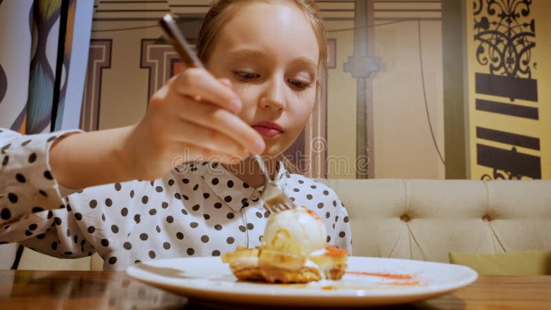 Девочка подростка портрета неунывающая есть сладкий десерт в кафе кондитерских изделий с мороженым.. Счастливая девочка подростка