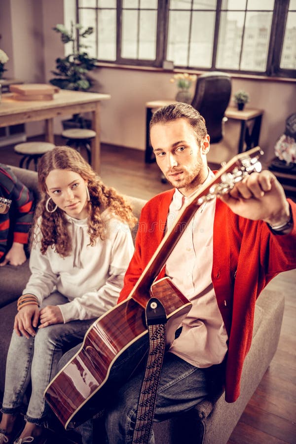 Девочка-подросток бородатого темн-с волосами гувернера гитары уча, который нужно сыграть стоковые изображения
