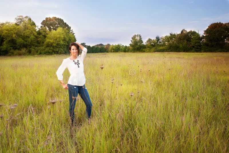 Девушка в джинсах стоя в поле