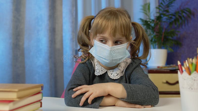 Девушка в медицинской маске, изучающая домашнюю работу во время онлайн урока дома с веб-камеры видеоматериал