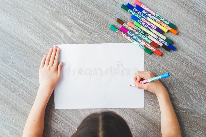 top view girl draws or writes on a white sheet with felt-tip pens, space for your text or drawing. top view girl draws or writes on a white sheet with felt-tip pens, space for your text or drawing.