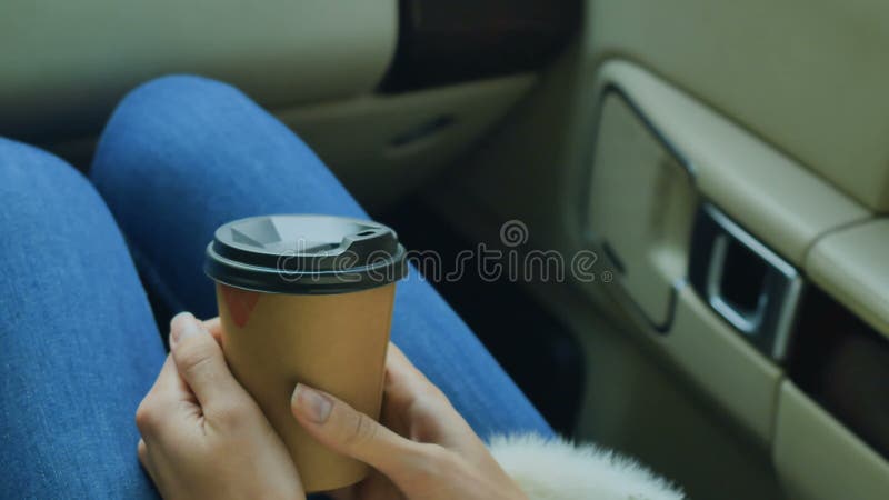 Девушка держит бумажное стекло кофе сидя внутри автомобиля видеоматериал
