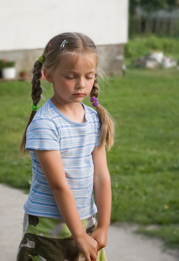 A cute girl outside a house, her eyes closed, shy expression. Both hands kept together. A cute girl outside a house, her eyes closed, shy expression. Both hands kept together.