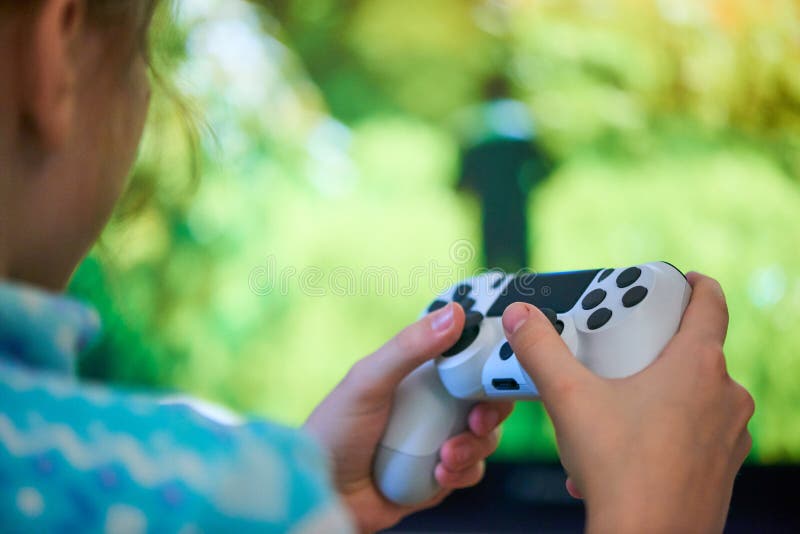 Девушка, играя в видеоигры с джойстиком дома стоковое фото