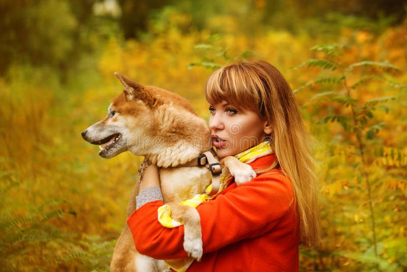 Девушка обнимает собаку Shiba Inu в парке осени стоковые фотографии rf Девушка обнимает собаку Shiba Inu в парке осени стоковые фотографии rf