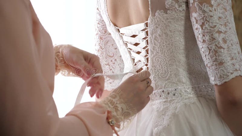Девушка одевает красивое белое платье для свадьбы