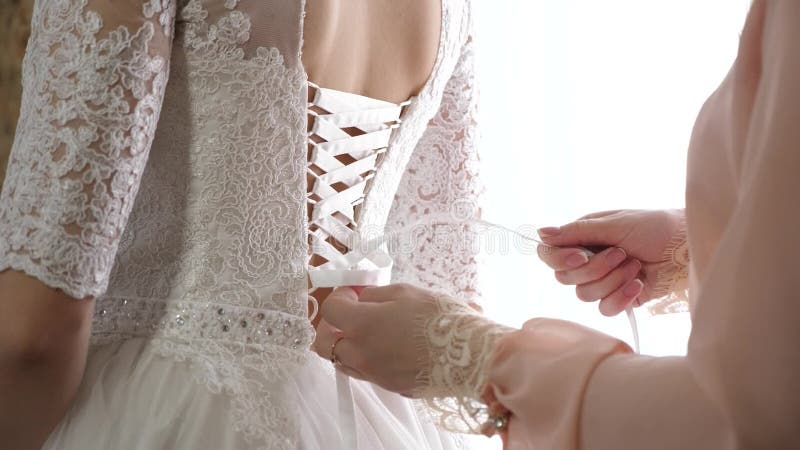 Девушка одевает красивое белое платье для свадьбы