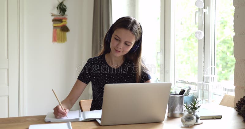 Девушка пишет в книге обучения студентов готовит эссе, используя компьютер