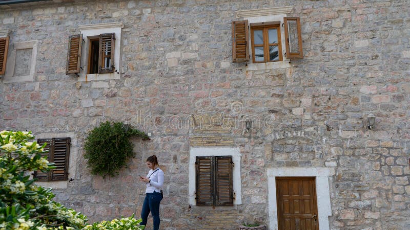 Girl with white long shirt sending a message in smart phone and stone house with flowers in the facade. Woman typing in cell phone. And wood windows in mediterranean town, texting, wall, conversation, traveler, people, smartphone, traditional, mobile, cellphone, lady, female, sms, chat, using, tourist, communication, online, technology, wooden. Girl with white long shirt sending a message in smart phone and stone house with flowers in the facade. Woman typing in cell phone. And wood windows in mediterranean town, texting, wall, conversation, traveler, people, smartphone, traditional, mobile, cellphone, lady, female, sms, chat, using, tourist, communication, online, technology, wooden