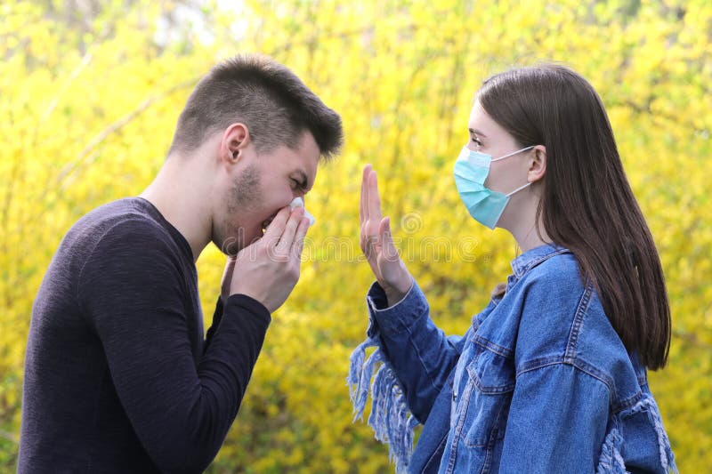Девушка с защитной маской и больной чихая мальчик, останавливают грипп e