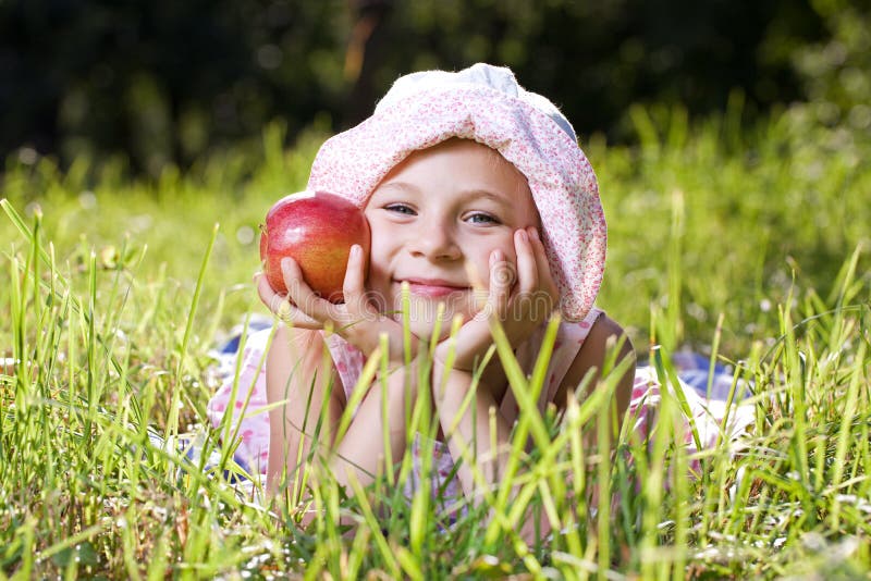 Girl with red apple lying in the grass. Girl with red apple lying in the grass