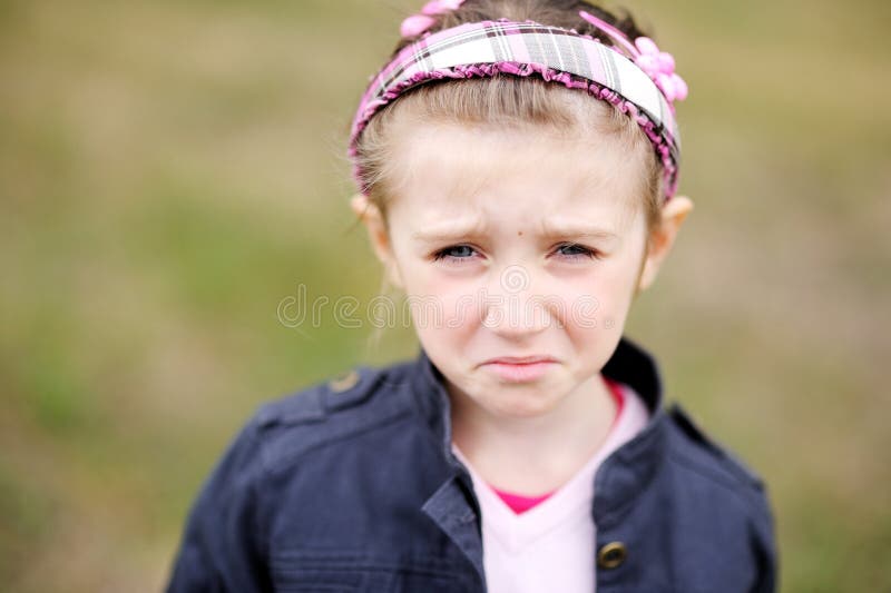 Cute child girl wearing pink headband makes upset weepy face. Cute child girl wearing pink headband makes upset weepy face