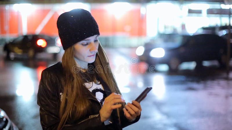 Девушка указывая палец на smartphone экрана на свете цвета bokeh освещенности фона в городе ночи атмосферическом видеоматериал Девушка указывая палец на smartphone экрана на свете цвета bokeh освещенности фона в городе ночи атмосферическом видеоматериал