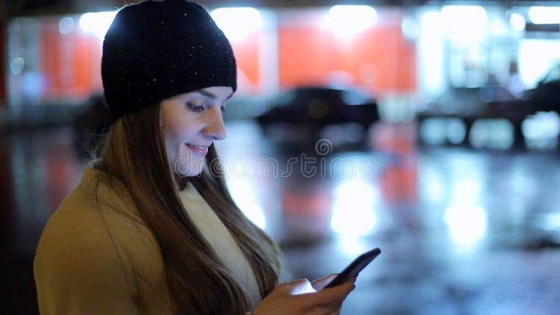 Девушка указывая палец на smartphone экрана на свете цвета bokeh освещенности фона в городе ночи атмосферическом сток-видео Девушка указывая палец на smartphone экрана на свете цвета bokeh освещенности фона в городе ночи атмосферическом сток-видео