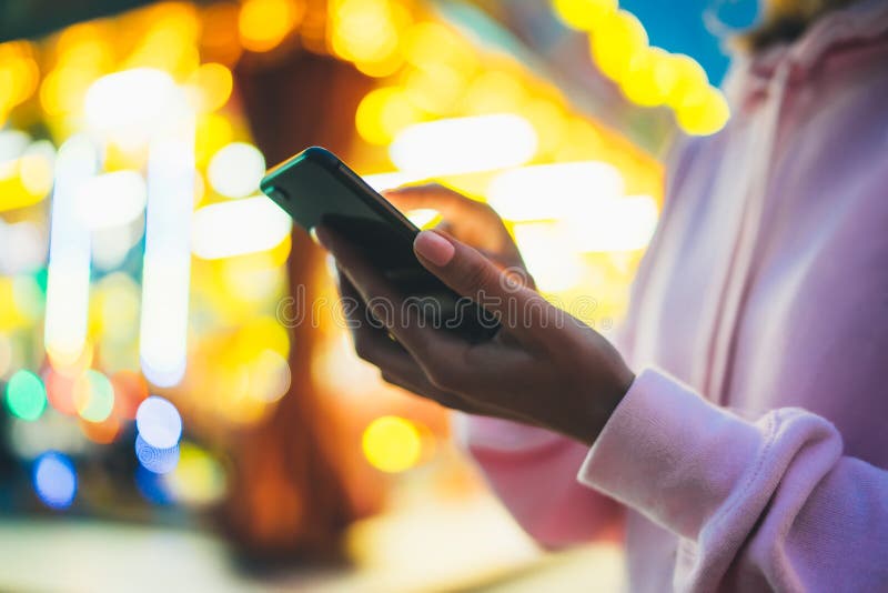 Девушка указывая палец на smartphone экрана на свете bokeh предпосылки в освещении города ночи атмосферическом в defoc улицы вече стоковые фотографии rf Девушка указывая палец на smartphone экрана на свете bokeh предпосылки в освещении города ночи атмосферическом в defoc улицы вече стоковые фотографии rf