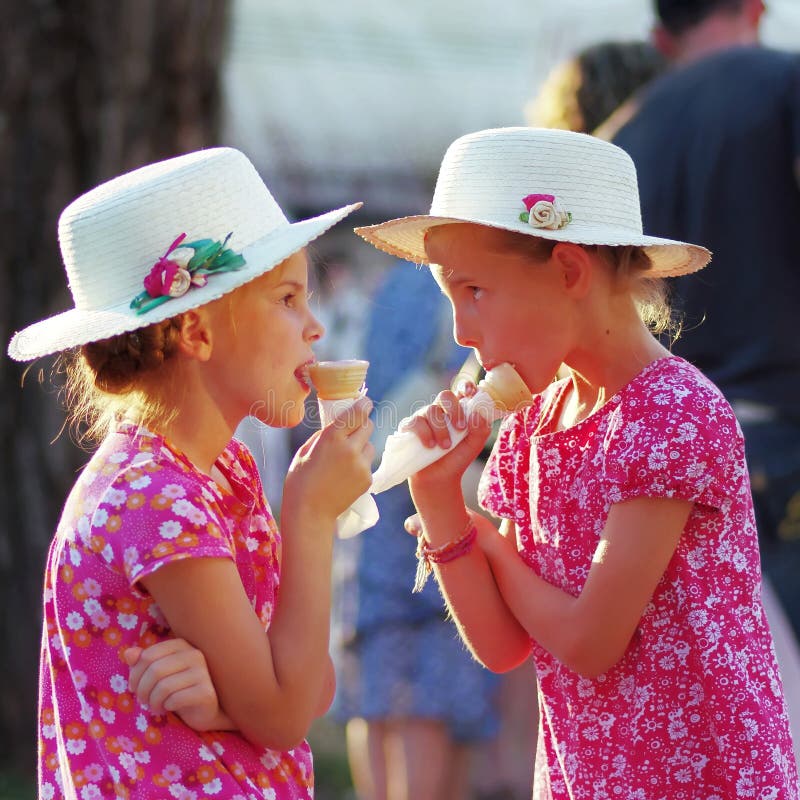 Unidentified beautiful sisters eating the icecream in the park on a sunny day. Unidentified beautiful sisters eating the icecream in the park on a sunny day.