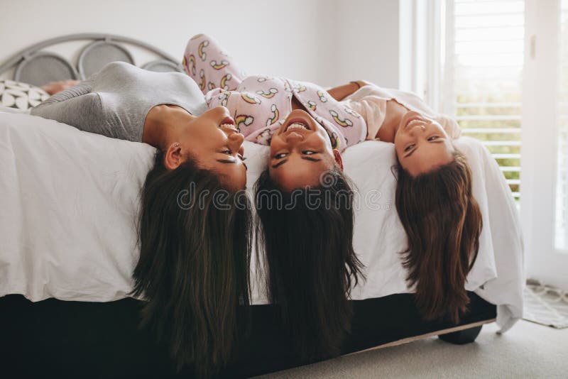 Девушки лежа на кровати имея потеху на sleepover стоковое изображение rf