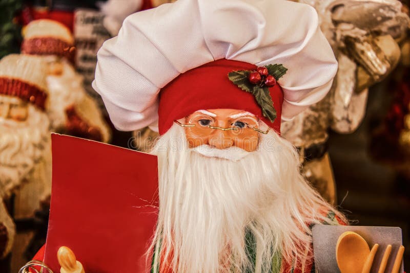 Декоративная кукла Санта в шапке для шефа, держащей в руках чистые таблички и кулинарные инструменты - близкий и выборочный фокус стоковое фото rf