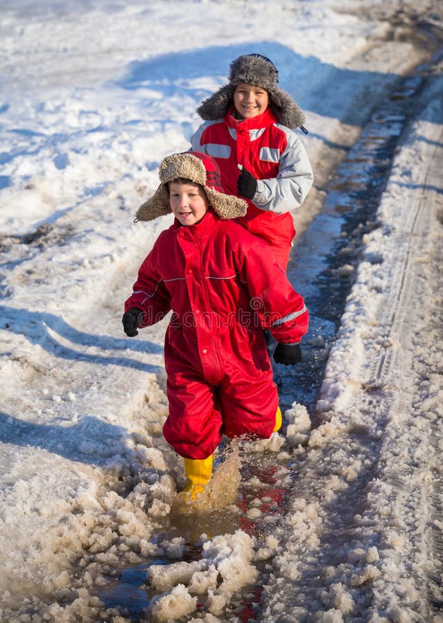 2 дет в rainboots бежать на льде puddle стоковое изображение 2 дет в rainboots бежать на льде puddle стоковое изображение