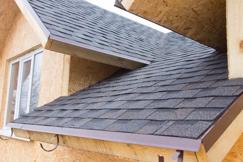 Detail of overlapping roofing tiles on a new build wooden house with dormer windows. Detail of overlapping roofing tiles on a new build wooden house with dormer windows