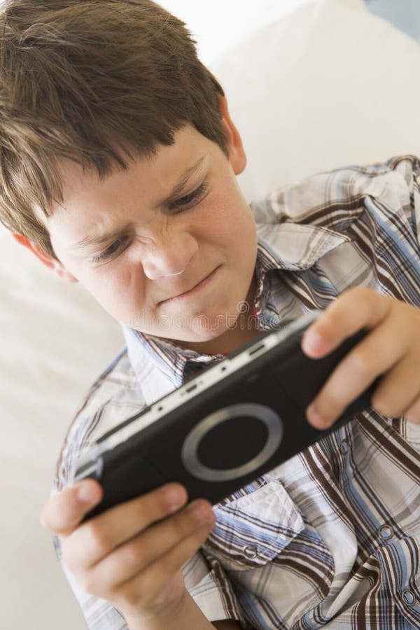 Young boy with handheld game indoors looking unhappy. Young boy with handheld game indoors looking unhappy