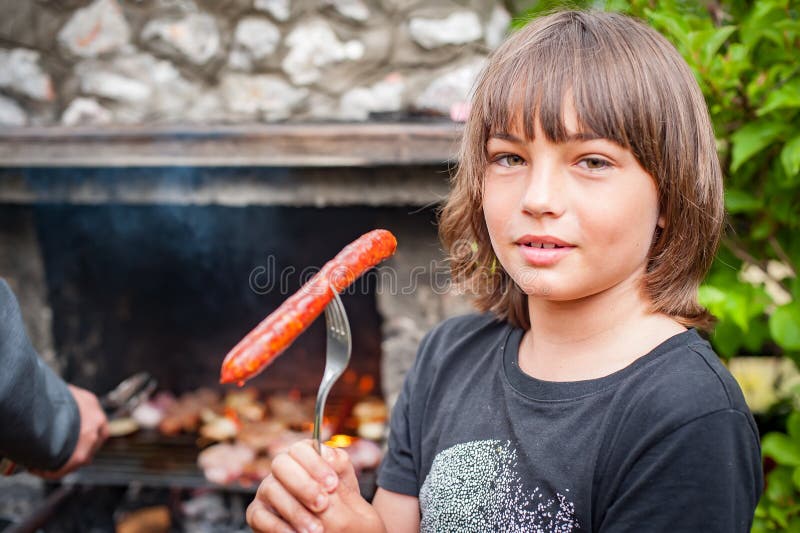 дети жарят мясо. счастливый мальчик-подросток делает барбекю в природе стоковое изображение rf