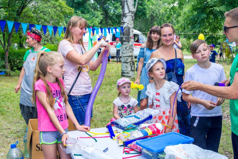 Дети и их родители раздувают воздушные шары на семейном благотворительном фестивале в городском парке стоковая фотография Дети и их родители раздувают воздушные шары на семейном благотворительном фестивале в городском парке стоковая фотография