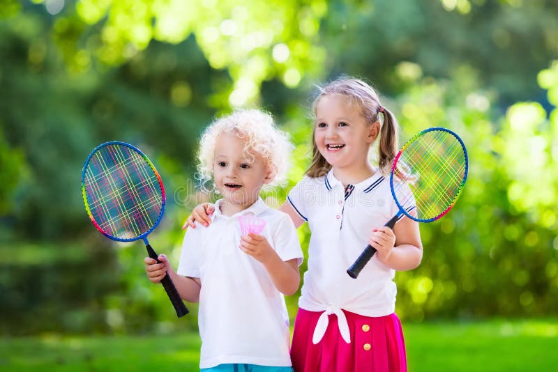 Active preschool girl and boy playing badminton in outdoor court in summer. Kids play tennis. School sports for children. Racquet and shuttlecock sport for child athlete. Kid with racket and shuttle. Active preschool girl and boy playing badminton in outdoor court in summer. Kids play tennis. School sports for children. Racquet and shuttlecock sport for child athlete. Kid with racket and shuttle.