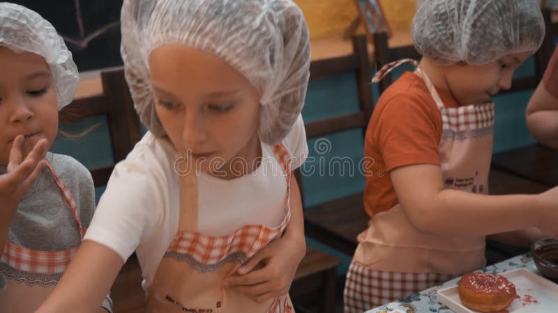 Дети, охватывающий пончики на кухне мастер-класс в кулинарной школе Подростки кухонную пончики с разноцветной поливой видеоматериал