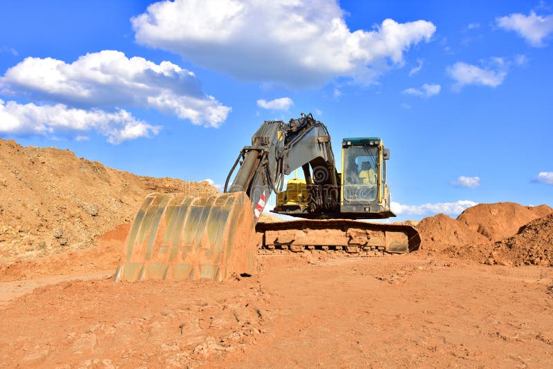 Деятельность экскаватора на earthmoving на добычу открытого карьера на фоне голубого неба. Экскаватор выкапывает песка в карьере. стоковое фото