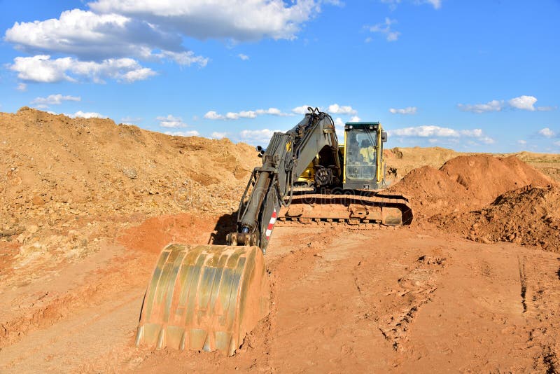 Деятельность экскаватора на earthmoving на добычу открытого карьера на фоне голубого неба. Экскаватор выкапывает песка в карьере. стоковая фотография