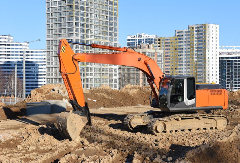 Деятельность экскаватора на стройке. Экскаватор на дорожной работе и earthworks. Earthmoving тяжелое оборудование для строительств стоковые изображения