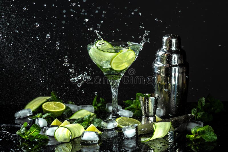 Cucumber gin and vodka alcohol cocktail. Infused summer mocktail with fresh, citrus fruit and cucumber, with liquid splash, freeze motion in jar glass on dark background. Cucumber gin and vodka alcohol cocktail. Infused summer mocktail with fresh, citrus fruit and cucumber, with liquid splash, freeze motion in jar glass on dark background.