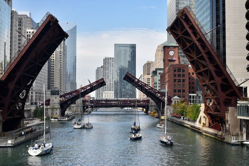 This is a Fall picture of the Dearborn Avenue and the Clark Street Bridges in a raised position allowing sailboats to move the Chicago River, in the background is the Wells Street Bridge with a Commuter train crossing it, located in Chicago, Illinois. The Dearborn Bridge was built in 1963, the Clark Street Bridge was built in 1927, and the Wells Street Bridge was built in 1922. This picture was taken on October 5, 2016. This is a Fall picture of the Dearborn Avenue and the Clark Street Bridges in a raised position allowing sailboats to move the Chicago River, in the background is the Wells Street Bridge with a Commuter train crossing it, located in Chicago, Illinois. The Dearborn Bridge was built in 1963, the Clark Street Bridge was built in 1927, and the Wells Street Bridge was built in 1922. This picture was taken on October 5, 2016.